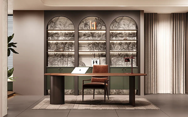 A modern home office setup featuring a long wooden desk with dark cylindrical legs, a matching brown leather chair, and a large built-in shelving unit behind it with three arched bays, patterned wallpaper, and warm ambient lighting.