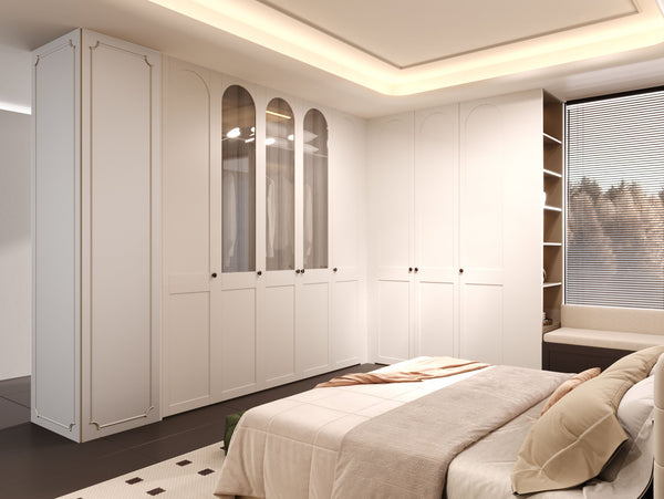 A modern bedroom featuring a large white built-in wardrobe with glass-front upper doors, shelving, and a matching bed with beige bedding.