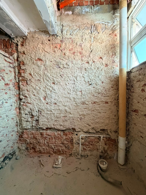 bathroom under renovation with exposed brick wall and floor.
